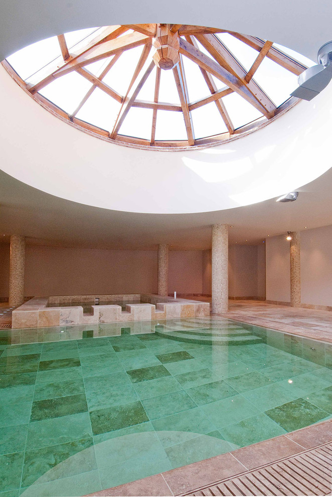 Inspiration pour une très grande piscine intérieure méditerranéenne rectangle avec un bain bouillonnant et des pavés en pierre naturelle.