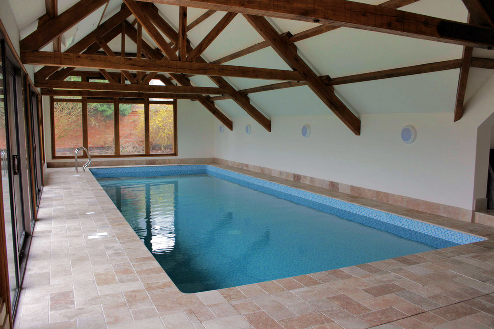 Photo of a medium sized rural indoor rectangular swimming pool in Other with a pool house and natural stone paving.