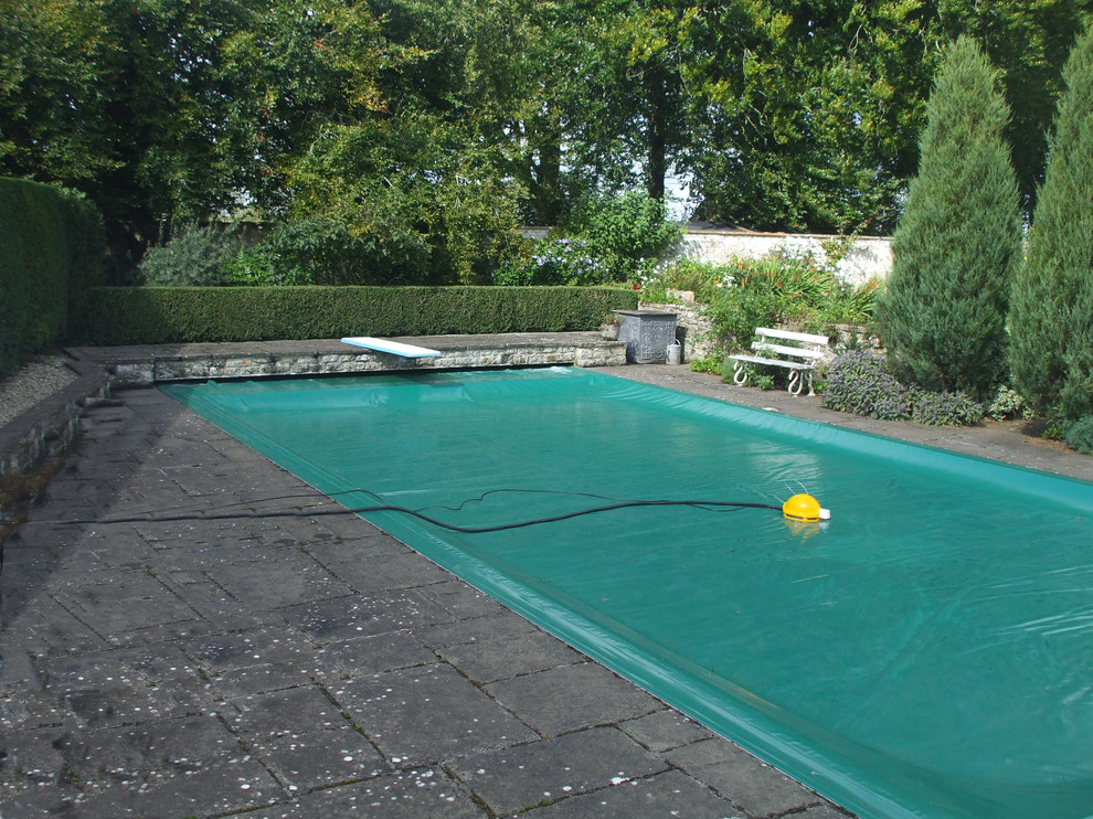 Modelo de piscina clásica de tamaño medio a medida en patio trasero con adoquines de piedra natural