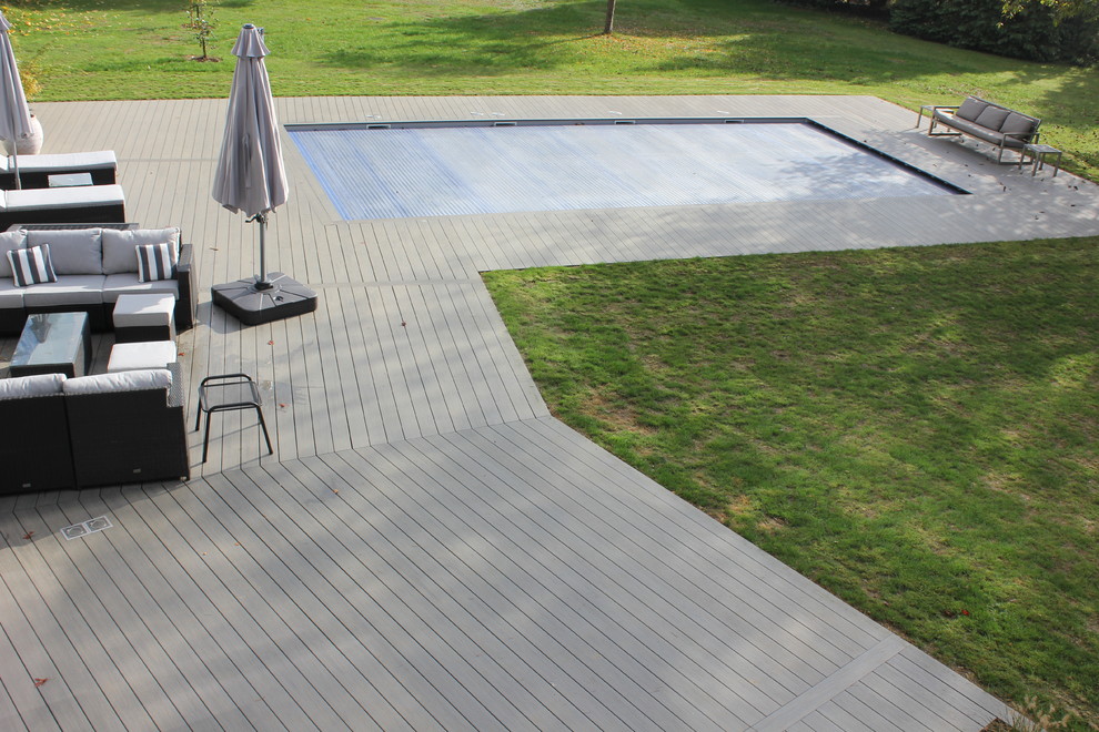 Aménagement d'une très grande piscine à débordement et arrière contemporaine rectangle avec une terrasse en bois.