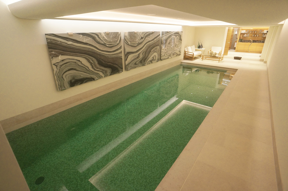 Cette image montre une grande piscine minimaliste rectangle avec des pavés en pierre naturelle.