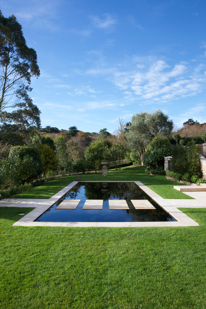 Diseño de piscina infinita tradicional renovada rectangular en patio trasero con adoquines de hormigón