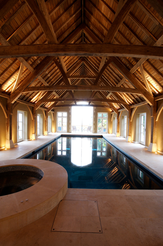 Immagine di una grande piscina coperta country rettangolare con pavimentazioni in pietra naturale e una vasca idromassaggio