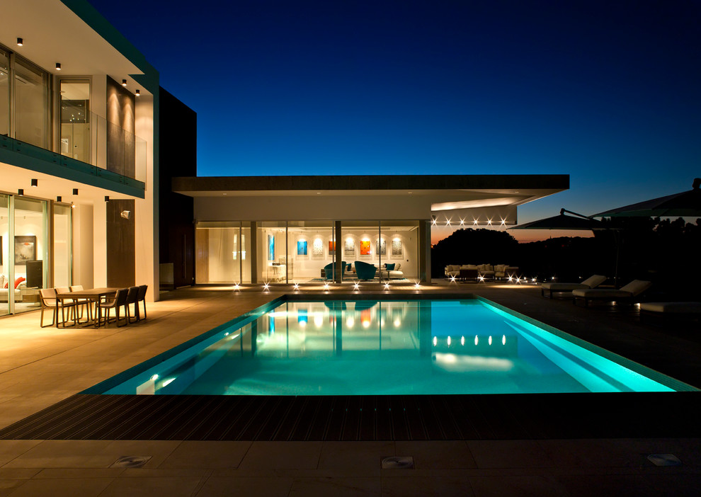 Diseño de piscina alargada contemporánea grande rectangular en patio trasero con suelo de baldosas