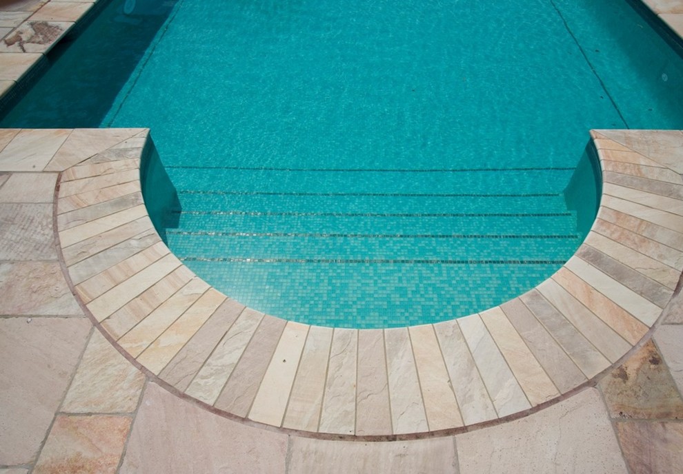 Diseño de piscina alargada mediterránea grande rectangular con adoquines de piedra natural