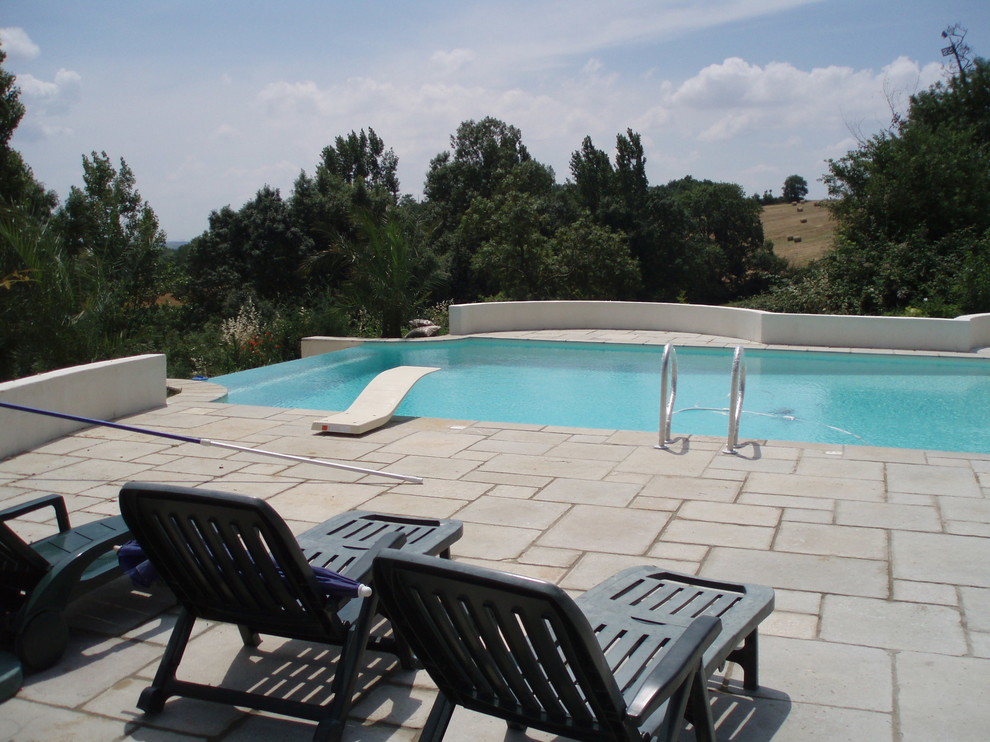 Diseño de piscina con fuente infinita mediterránea de tamaño medio rectangular en azotea con adoquines de piedra natural