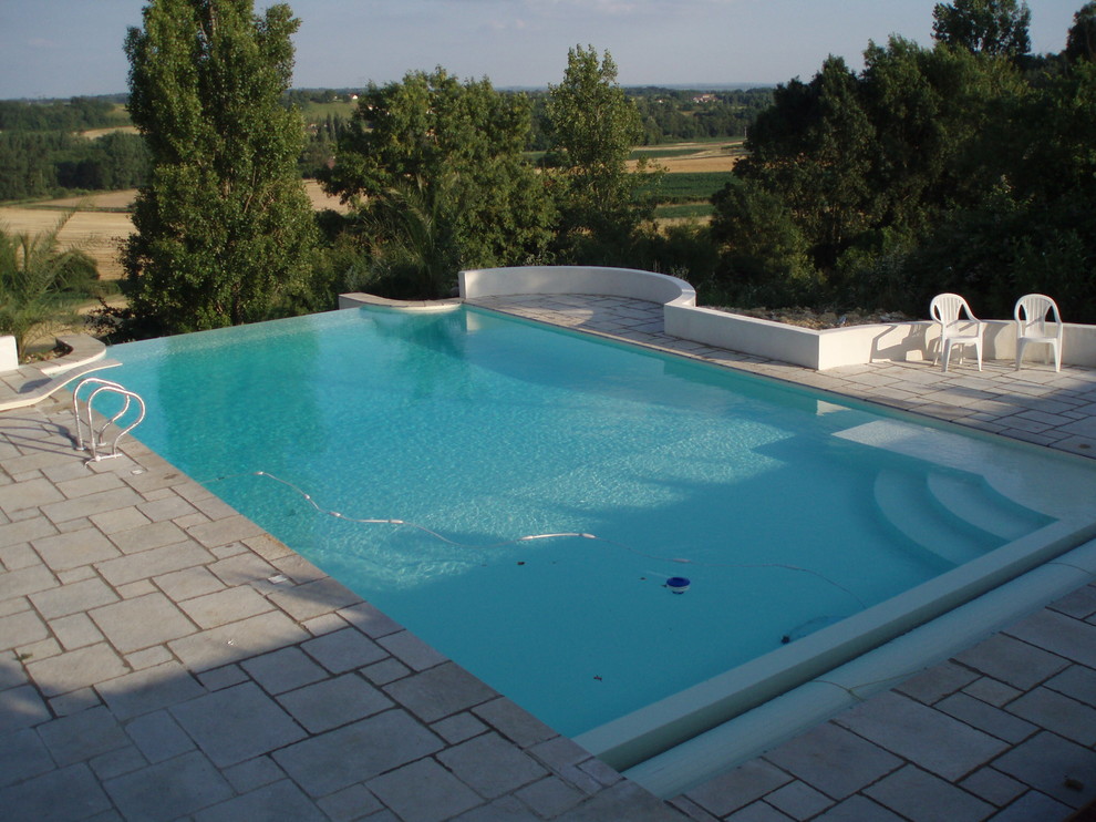 Cette photo montre une piscine sur toit à débordement méditerranéenne de taille moyenne et rectangle avec un point d'eau et des pavés en pierre naturelle.