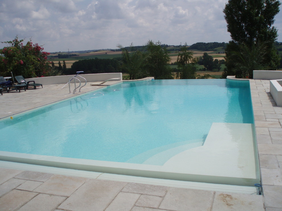 Idées déco pour une piscine sur toit à débordement méditerranéenne de taille moyenne et rectangle avec un point d'eau et des pavés en pierre naturelle.
