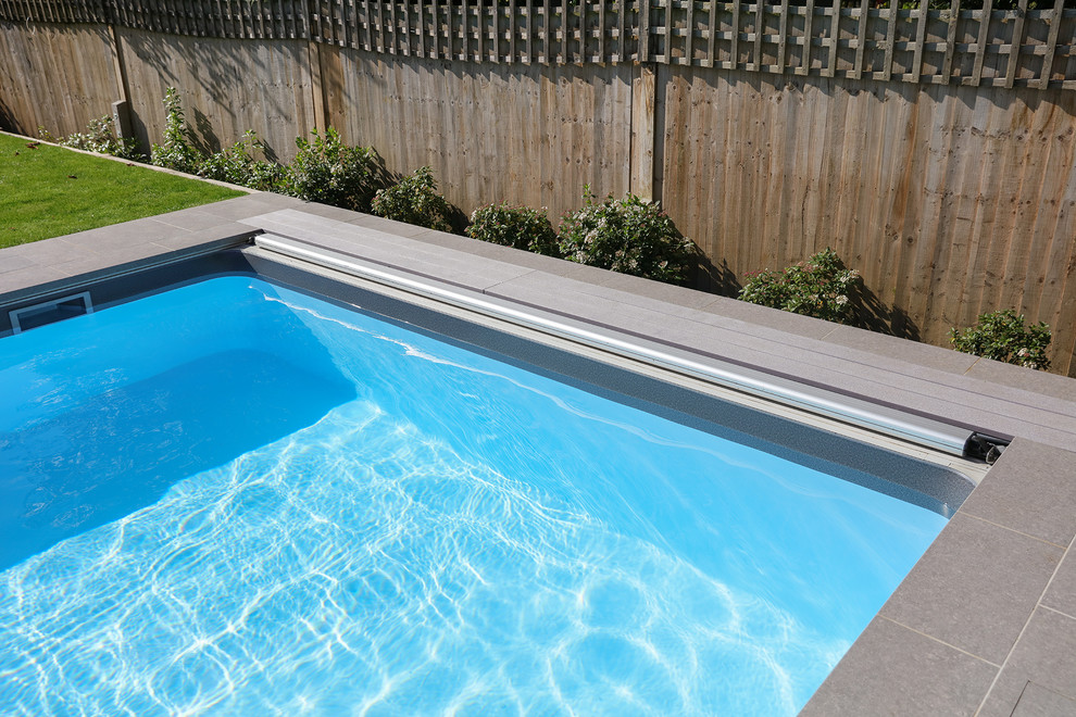 Foto di una piscina moderna rettangolare di medie dimensioni e dietro casa con piastrelle