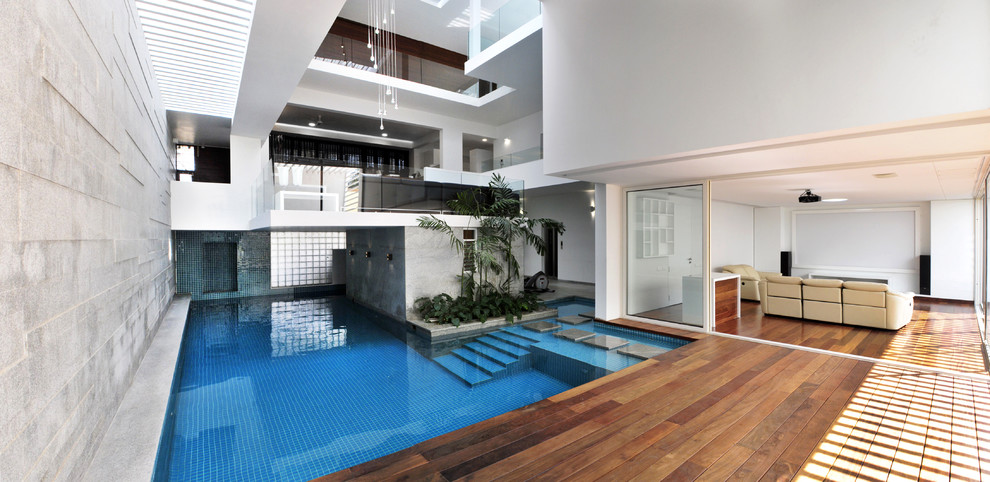 Diseño de piscina actual grande interior y en forma de L con entablado