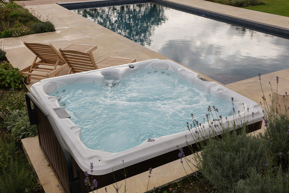 Idee per una grande piscina fuori terra contemporanea rettangolare dietro casa con piastrelle e una vasca idromassaggio