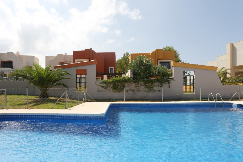 Foto di una piccola piscina mediterranea a "L" dietro casa con fontane e lastre di cemento