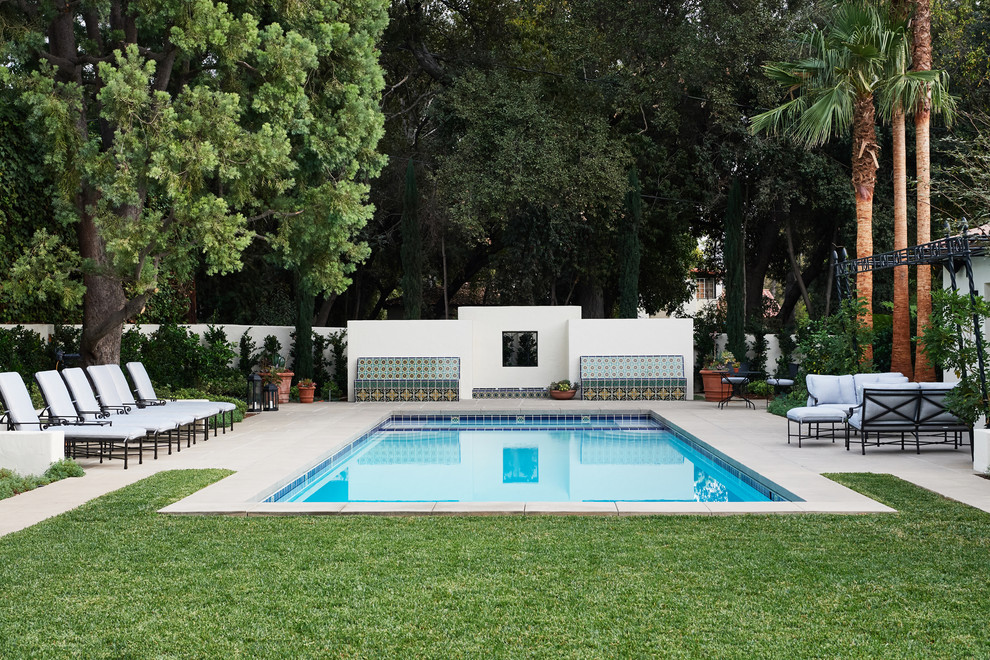Modelo de piscina alargada mediterránea grande rectangular en patio trasero con adoquines de hormigón