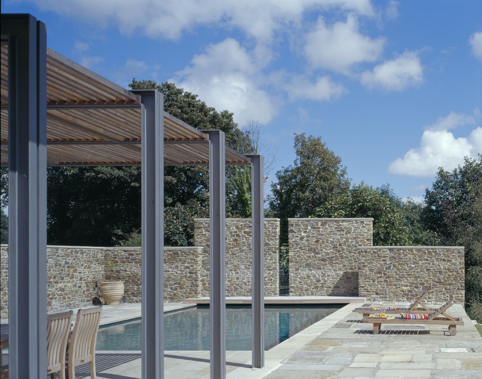 Ejemplo de piscina actual rectangular en patio trasero con adoquines de piedra natural