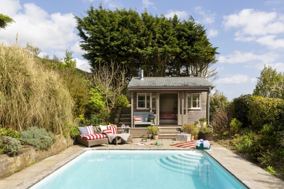 Ejemplo de piscina alargada de estilo de casa de campo de tamaño medio rectangular en patio trasero con adoquines de piedra natural