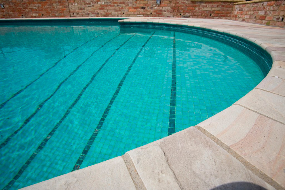 Diseño de piscina natural de estilo de casa de campo de tamaño medio rectangular en patio trasero con suelo de baldosas