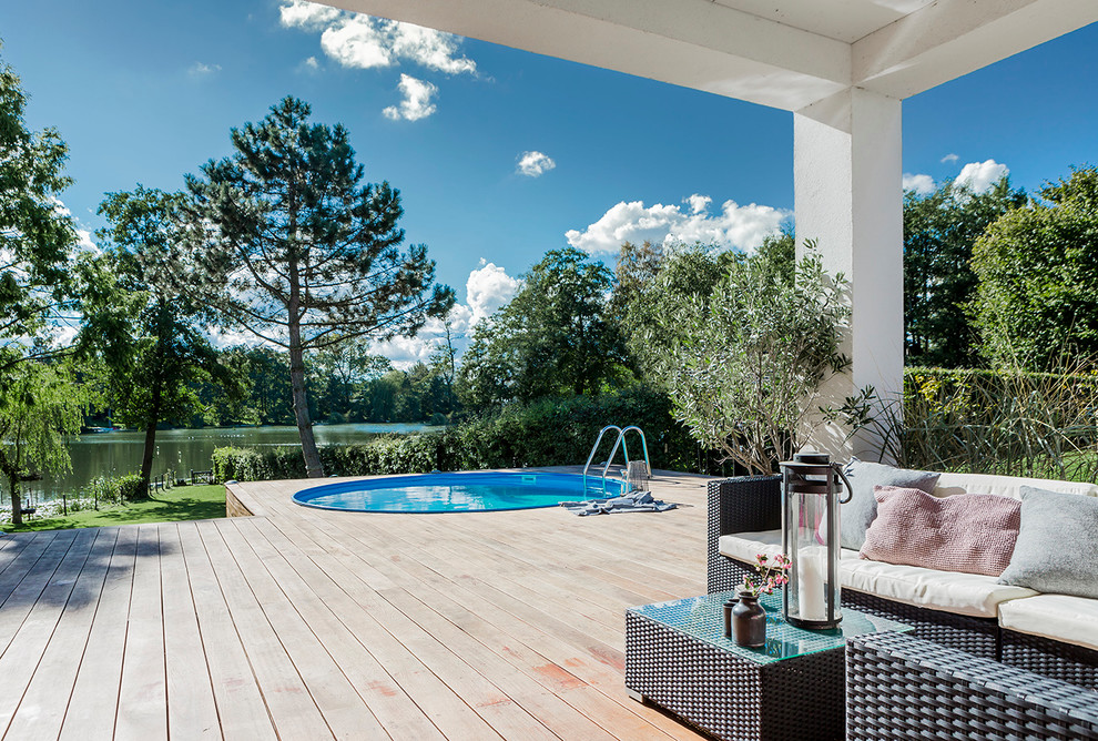 Inspiration pour une grande piscine arrière design ronde avec une terrasse en bois.