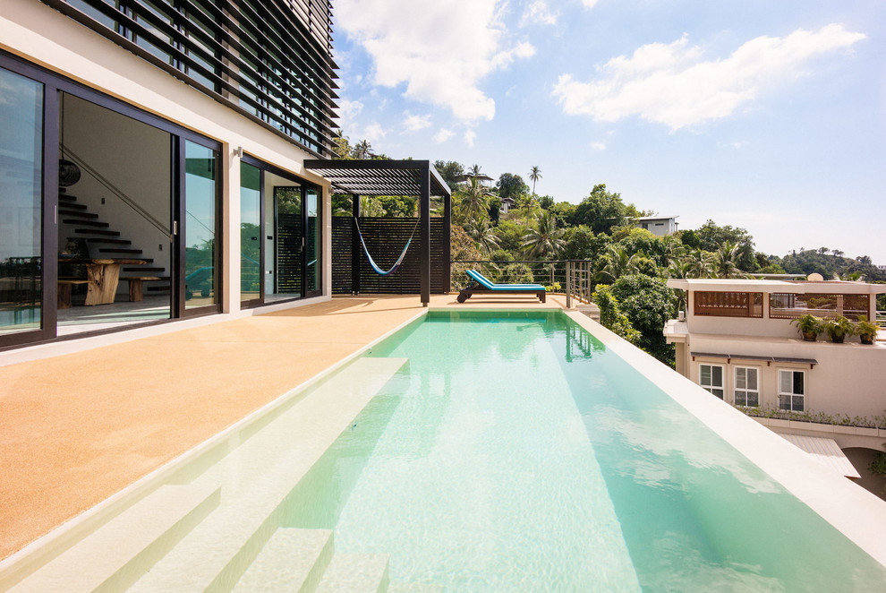 Diseño de piscina con tobogán infinita marinera de tamaño medio rectangular en patio trasero con suelo de baldosas