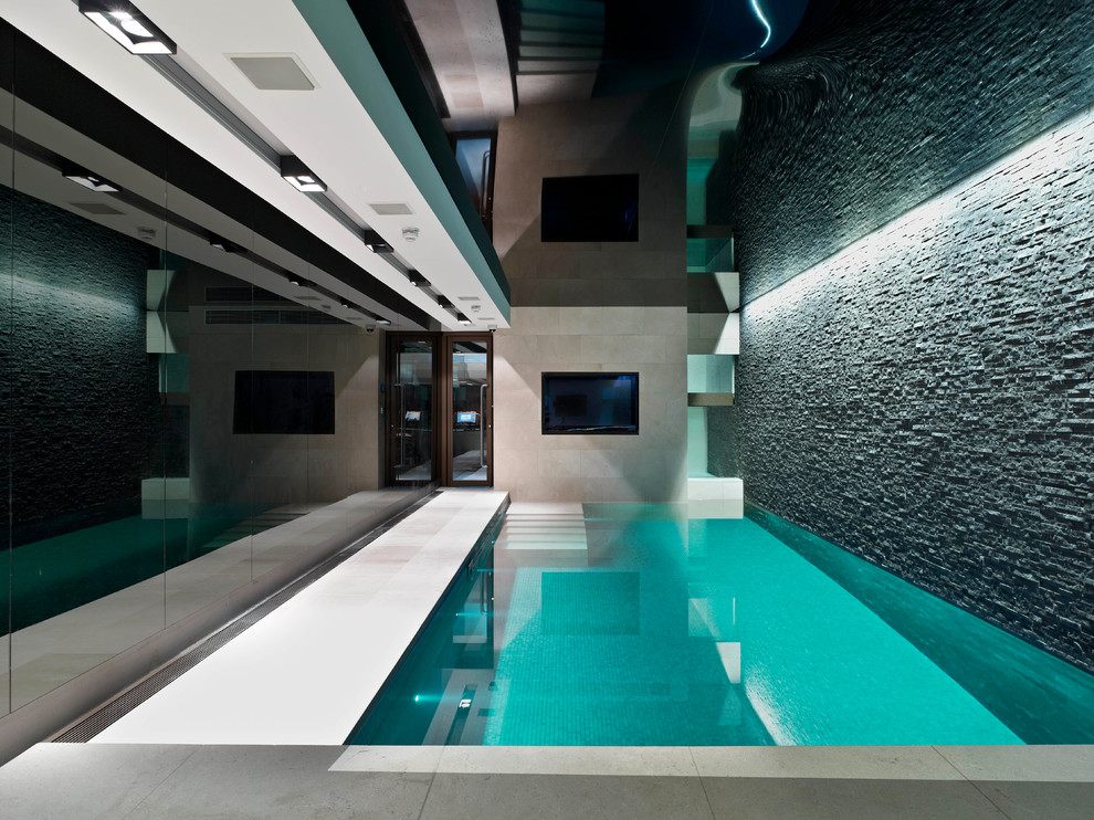 Medium sized contemporary indoor rectangular swimming pool in London with natural stone paving.