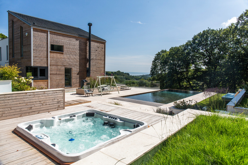 Immagine di una piscina a sfioro infinito country rettangolare dietro casa con una vasca idromassaggio