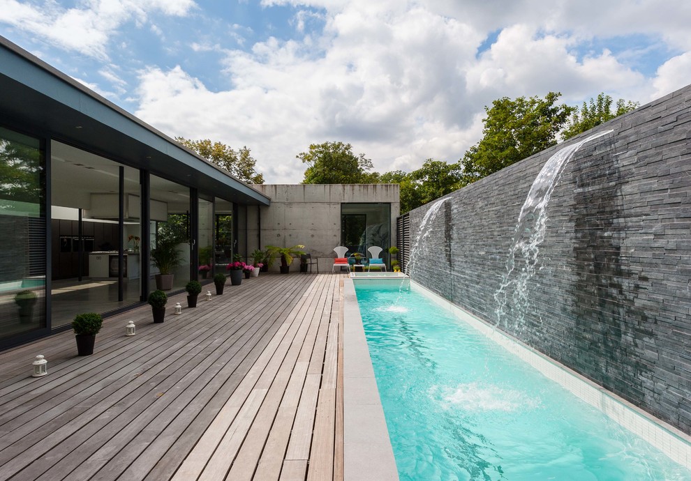 Идея дизайна: прямоугольный, спортивный бассейн в современном стиле с настилом и фонтаном