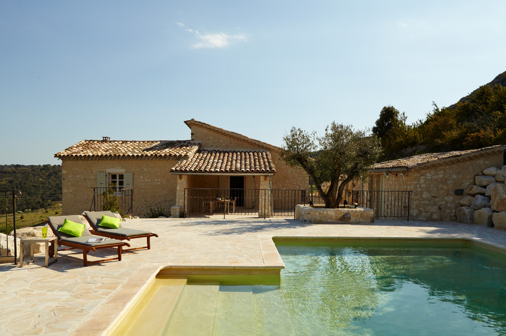 Ispirazione per una piscina mediterranea a "L" di medie dimensioni e dietro casa con pavimentazioni in pietra naturale