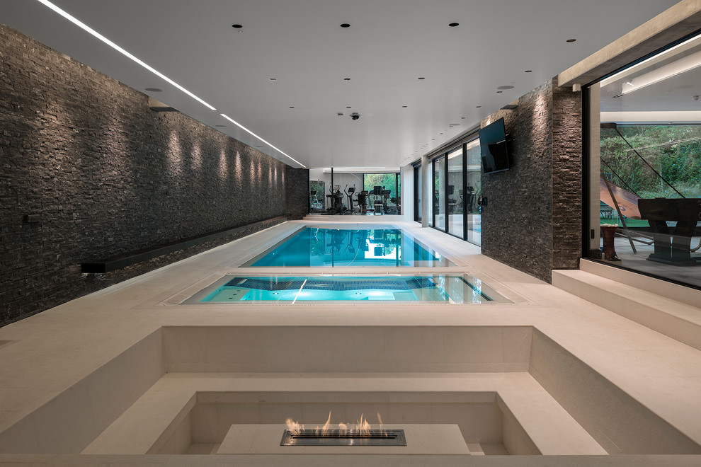 Idee per un'ampia piscina coperta minimal rettangolare con una vasca idromassaggio e pavimentazioni in pietra naturale