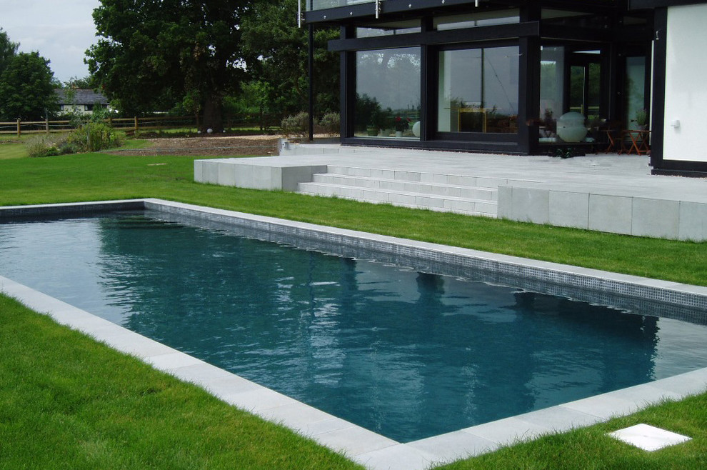 This is an example of a small modern back rectangular natural swimming pool in Hampshire with tiled flooring.