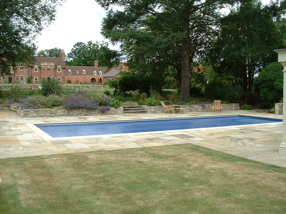 Imagen de piscina clásica grande rectangular en patio trasero con adoquines de piedra natural