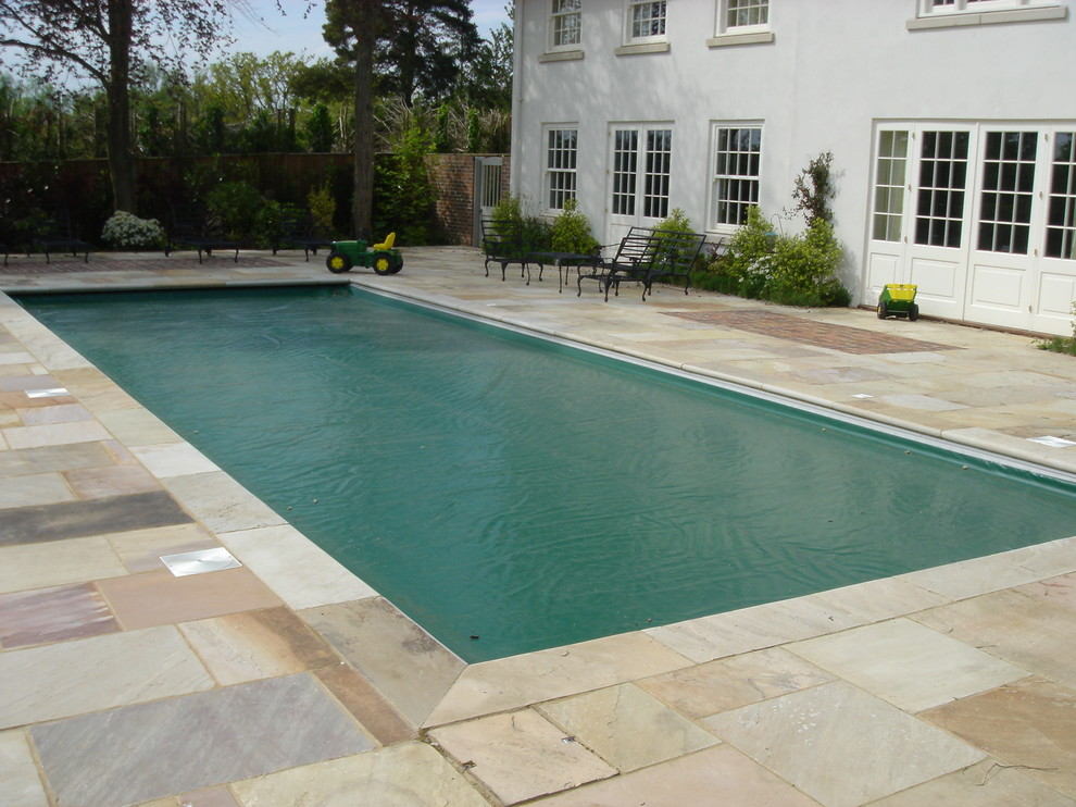 Diseño de piscina alargada clásica de tamaño medio rectangular en patio con adoquines de piedra natural