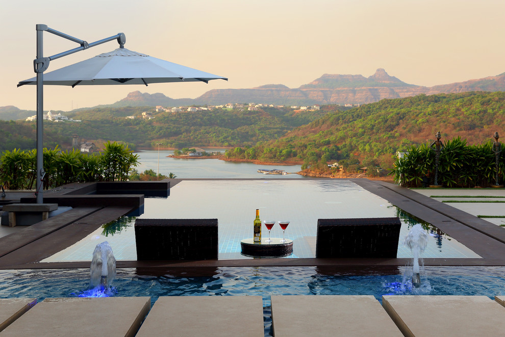 This is an example of a contemporary rectangular swimming pool in Pune with a water feature.