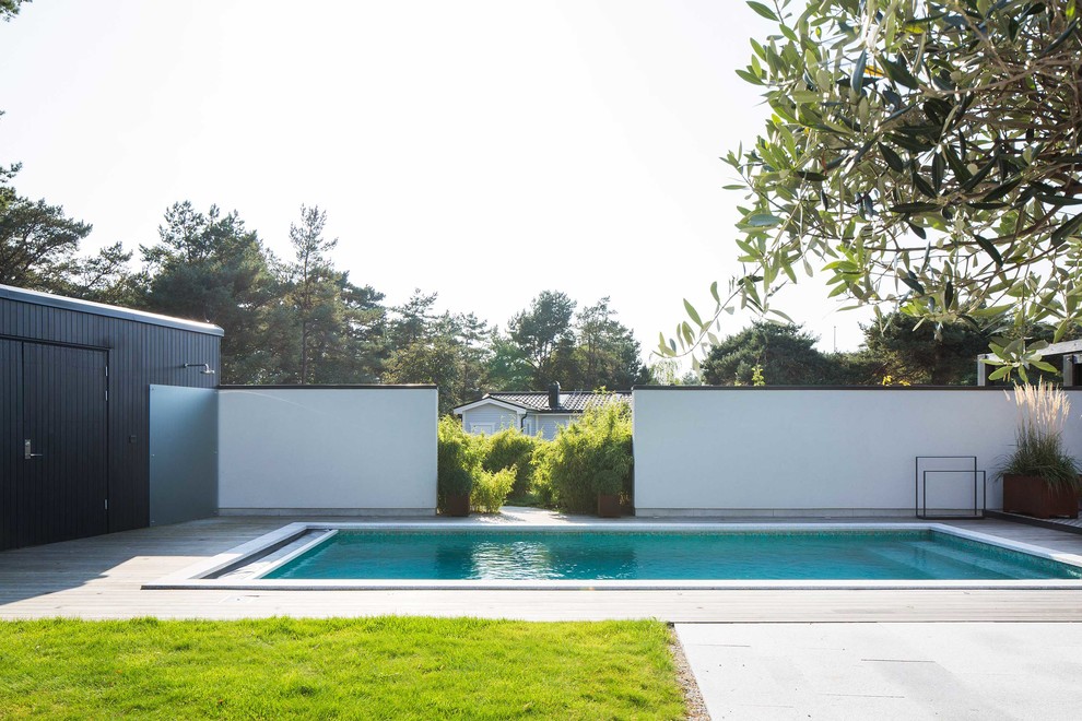 Inspiration för stora moderna rektangulär pooler på baksidan av huset, med trädäck