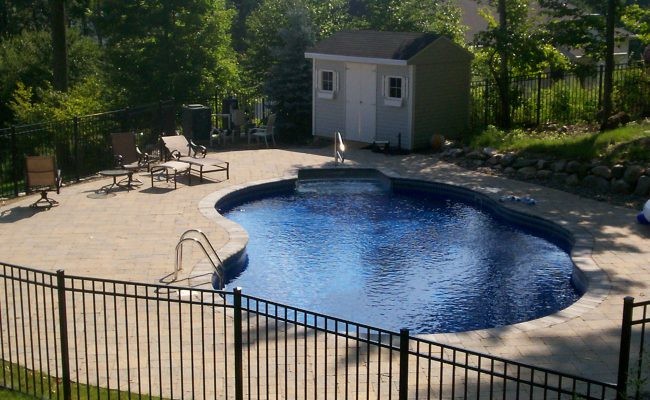 Medium sized traditional back custom shaped lengths swimming pool in New York with a pool house and brick paving.