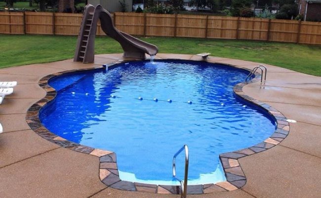 Modelo de piscina con tobogán alargada clásica de tamaño medio a medida en patio trasero con granito descompuesto