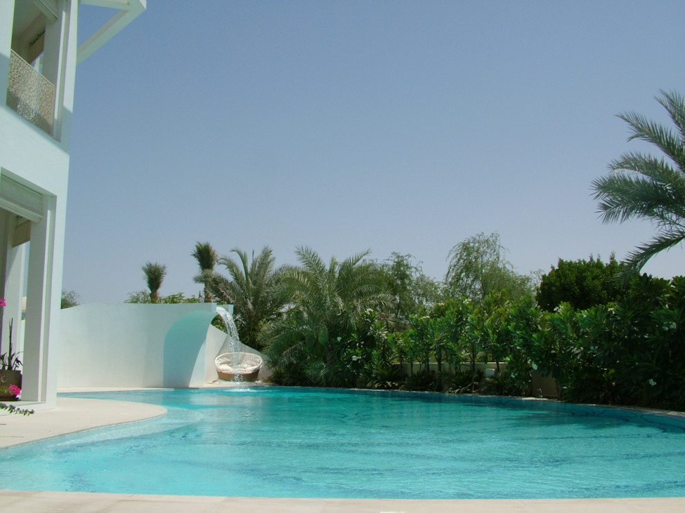 Großer Moderner Infinity-Pool hinter dem Haus in individueller Form mit Wasserspiel und Betonplatten in Sonstige