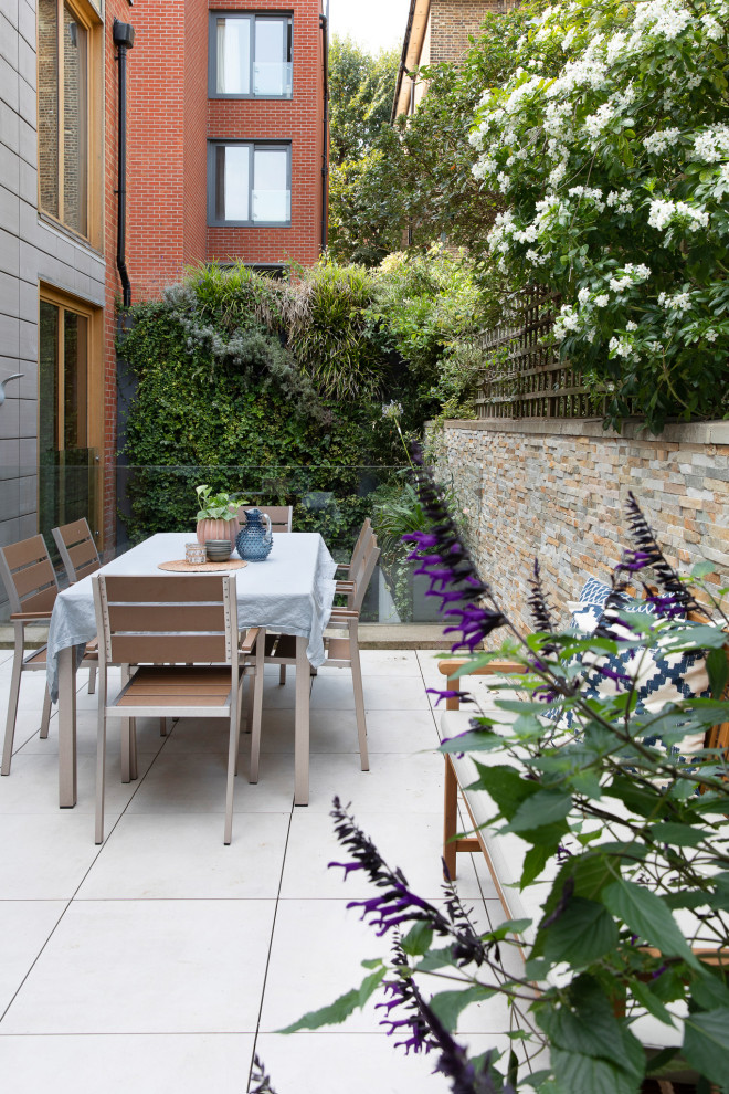 Modelo de terraza contemporánea pequeña sin cubierta en patio con jardín vertical y barandilla de vidrio