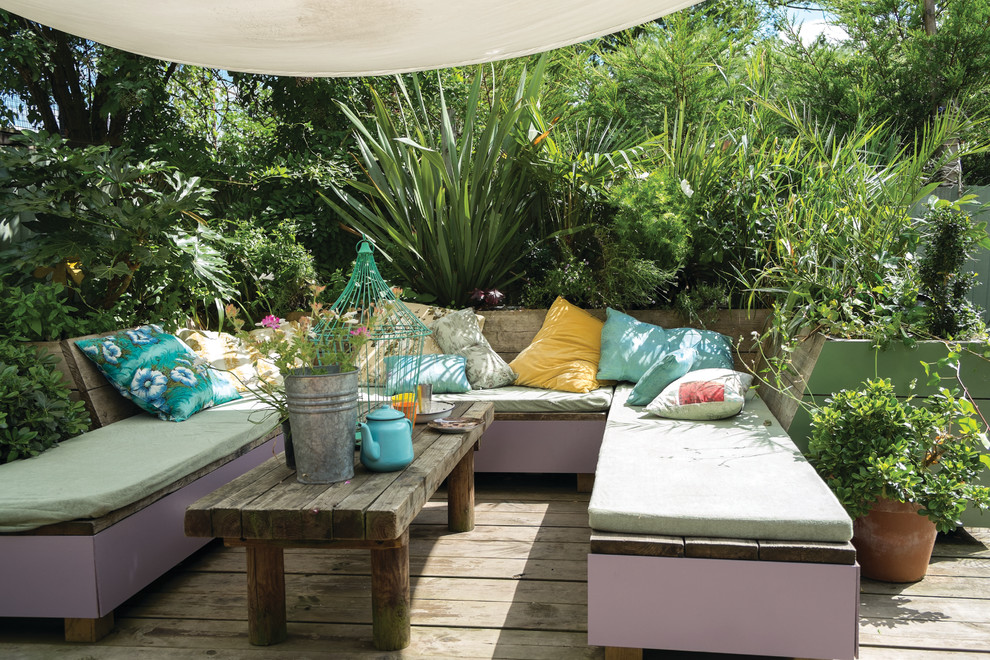 Modelo de terraza bohemia en patio trasero con jardín de macetas y toldo