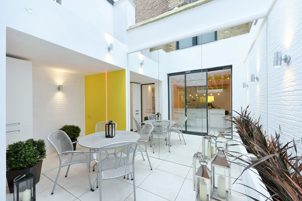 Medium sized modern side terrace in London with a potted garden and a roof extension.