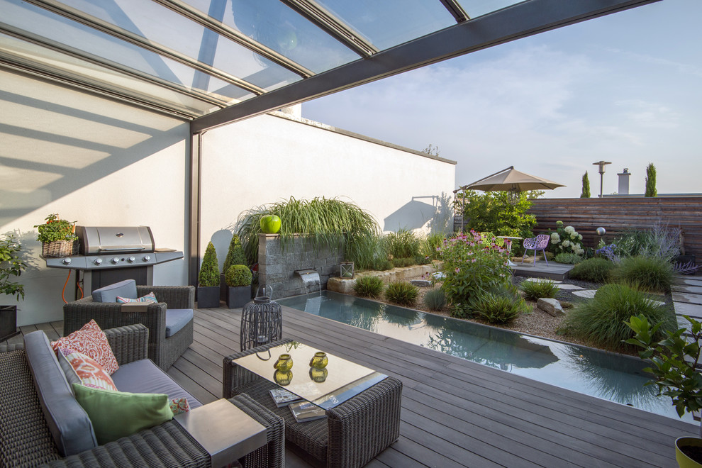 This is an example of a large contemporary terrace in Munich with an outdoor kitchen and a pergola.