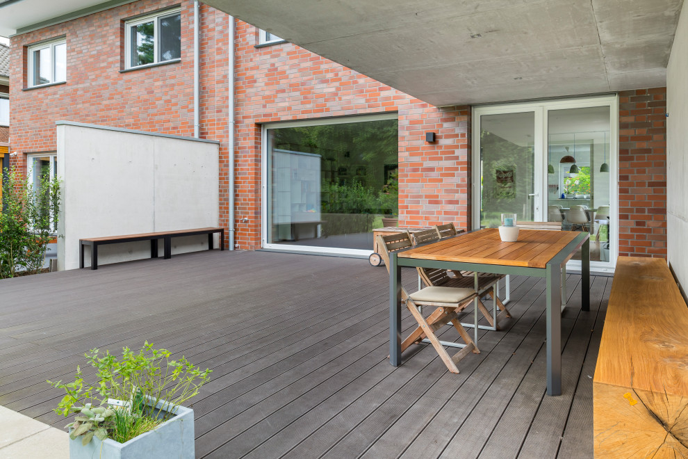 Réalisation d'une terrasse latérale design de taille moyenne avec une extension de toiture.