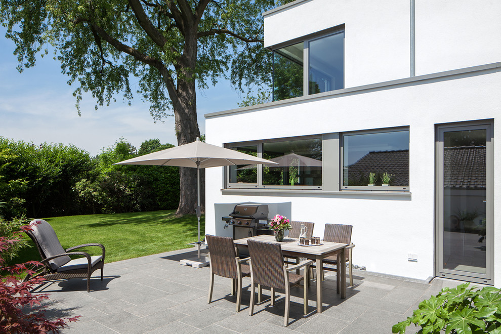This is an example of a medium sized contemporary side patio in Essen with tiled flooring, no cover and a bbq area.