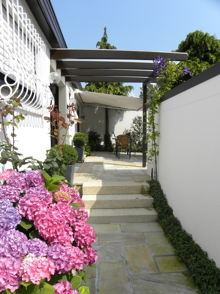 Esempio di una terrazza country di medie dimensioni e dietro casa con un giardino in vaso e una pergola