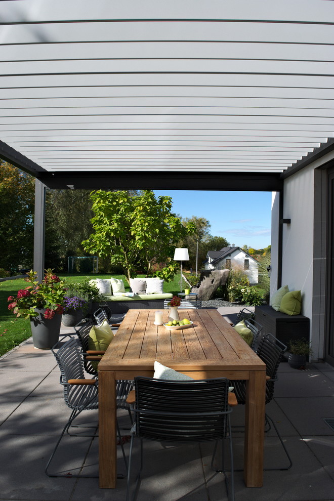 Immagine di una terrazza design di medie dimensioni e dietro casa con un giardino in vaso e un tetto a sbalzo