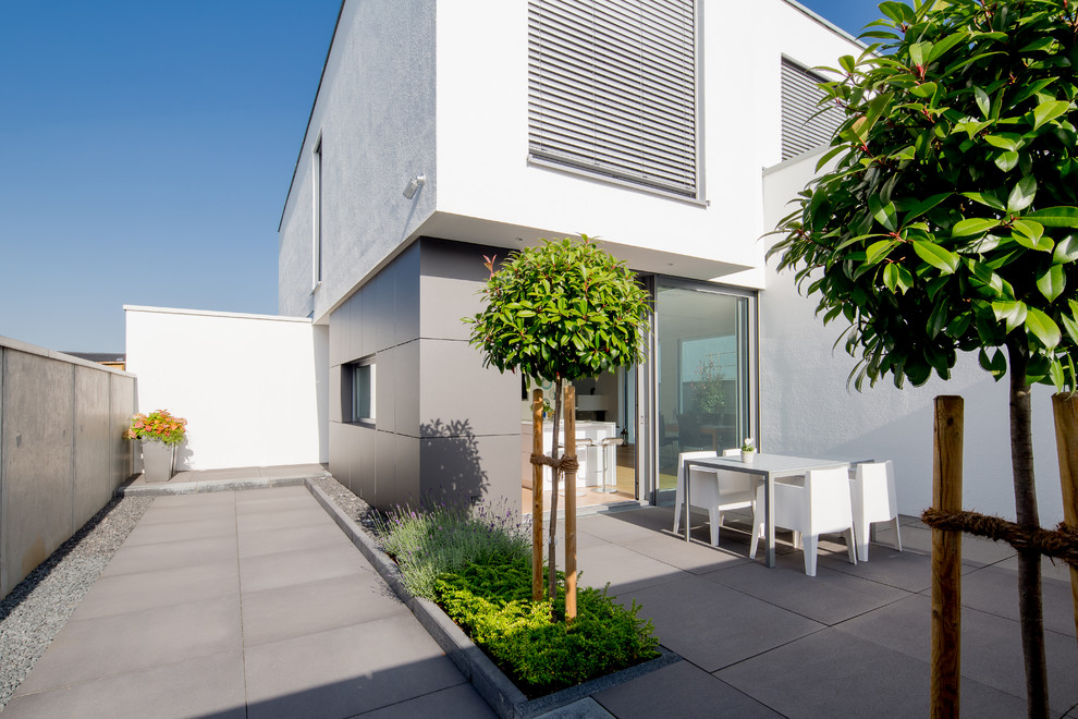 Idee per una terrazza design nel cortile laterale e di medie dimensioni con un giardino in vaso e un tetto a sbalzo