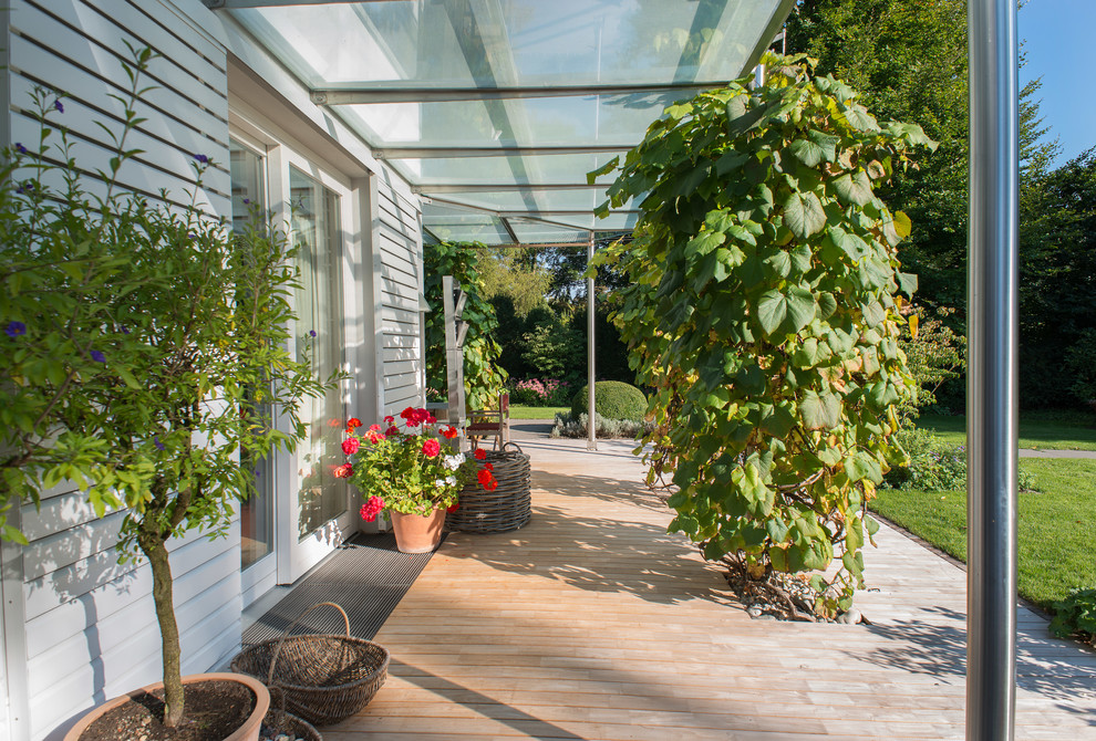 Cette photo montre une terrasse avec des plantes en pots latérale tendance de taille moyenne avec une extension de toiture.