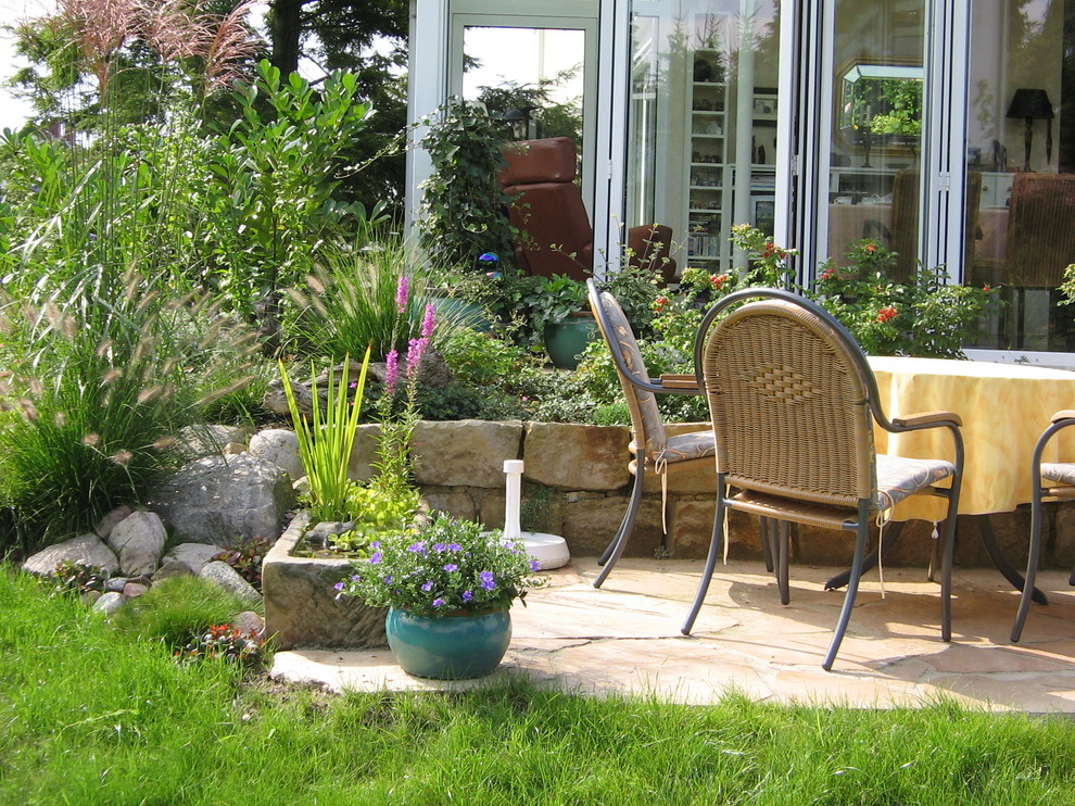 Diseño de terraza de estilo de casa de campo pequeña sin cubierta en patio trasero con jardín de macetas