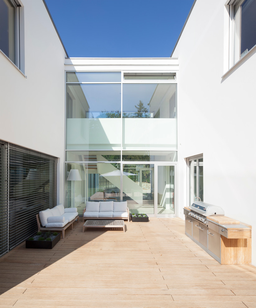На фото: огромная терраса на боковом дворе в стиле модернизм с зоной барбекю без защиты от солнца с
