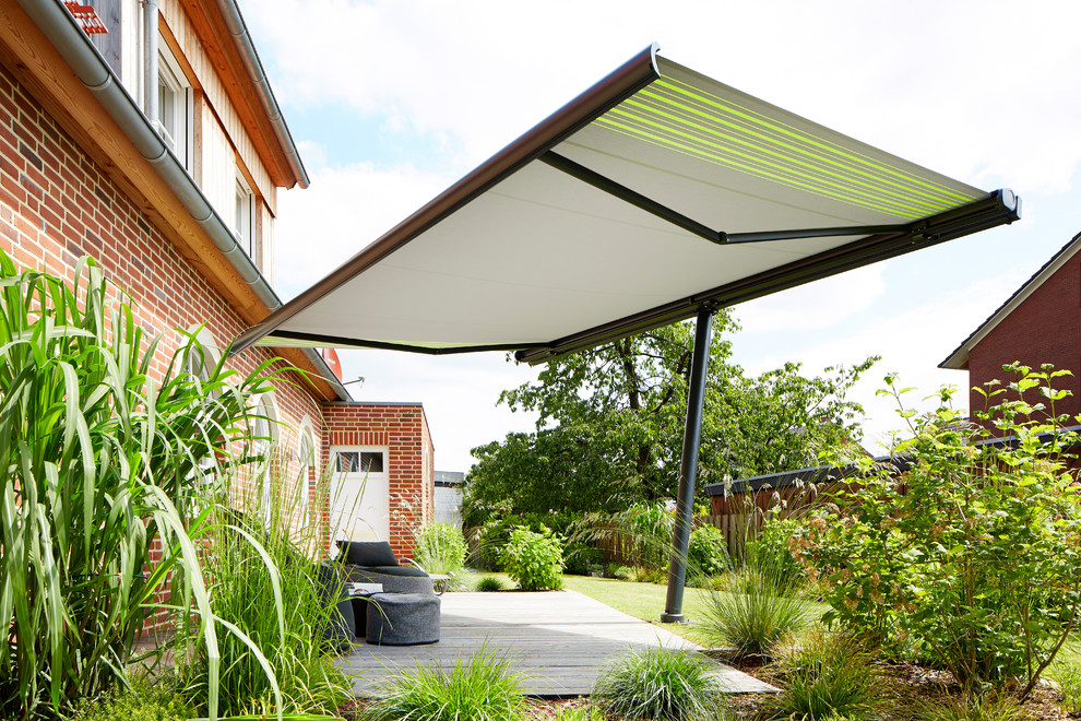 This is an example of a medium sized traditional back terrace in Other with an awning and a living wall.