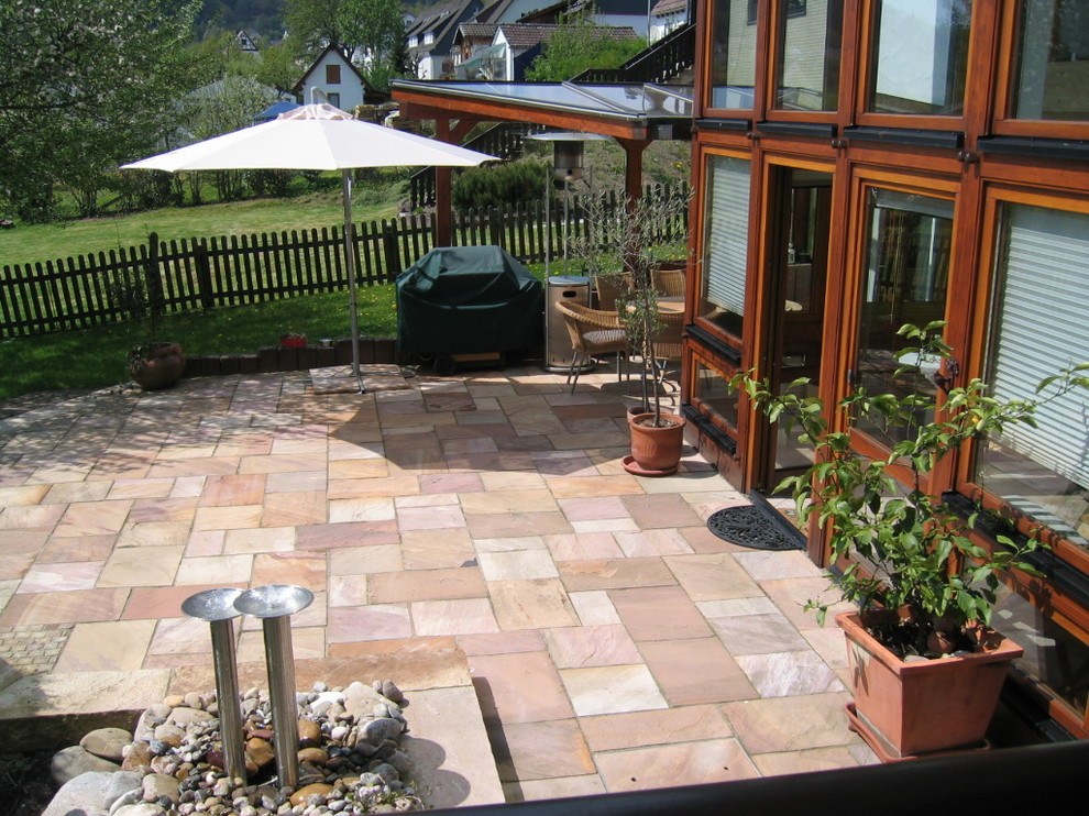 Immagine di un grande patio o portico mediterraneo dietro casa con un giardino in vaso e un tetto a sbalzo