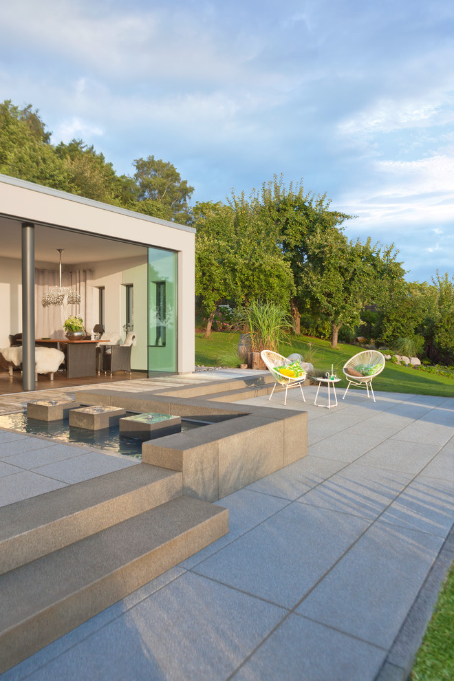 Diseño de terraza actual de tamaño medio sin cubierta en patio trasero con fuente